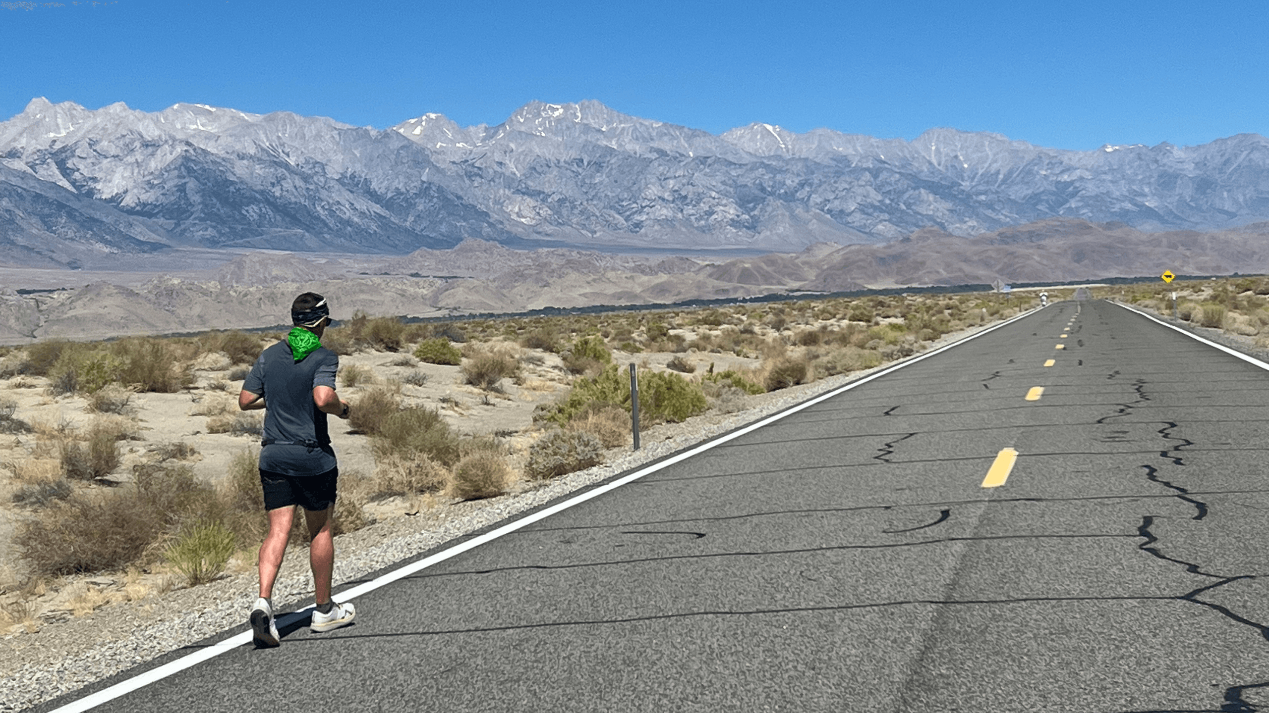 Person running on a road with mountains in the background