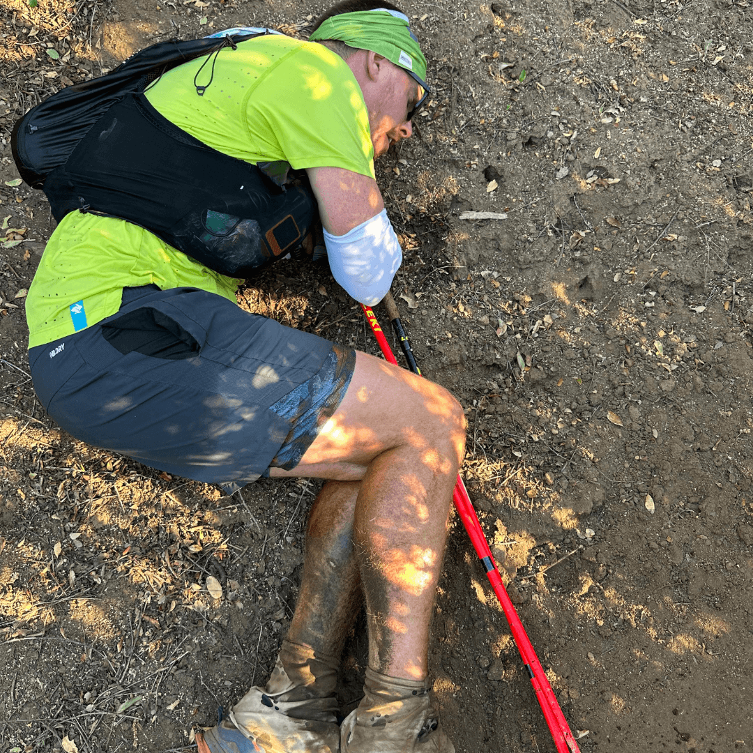 DNF Running Lessons: Runner on the laying on a dirt trail in fetal position vomiting.
