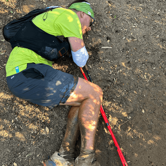 DNF Running Lessons: Runner on the laying on a dirt trail in fetal position vomiting.