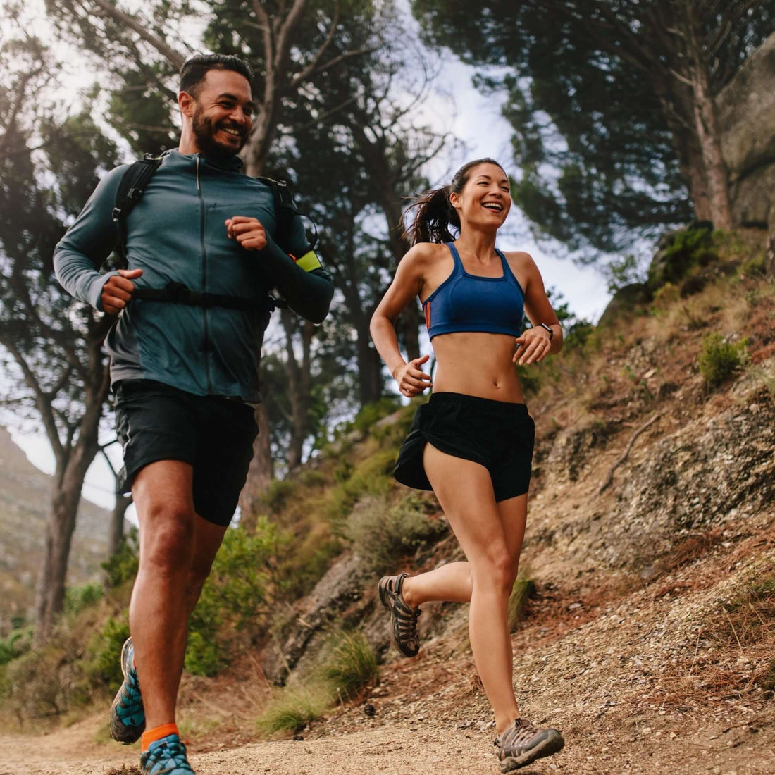 trail runners, a man and a woman run on a dirt path.